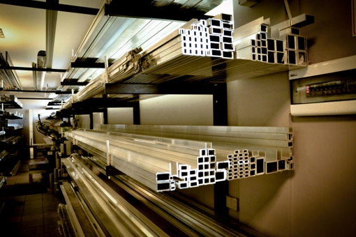 Półki w magazynie z rurami i profilami aluminiowymi