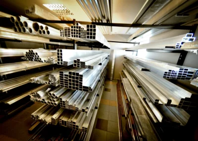 Wnętrze magazynu z regałami pełnymi różnych profili aluminiowych